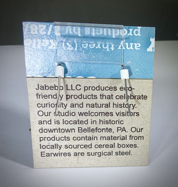 Back of earring card reading, Jabebo LLC produces eco-friendly products that celebrate curiosity and natural history. Our studio welcomes visitors and is located in historic downtown Bellefonte, PA. Our products contain material from locally sourced cereal boxes. Earwires are surgical steel.